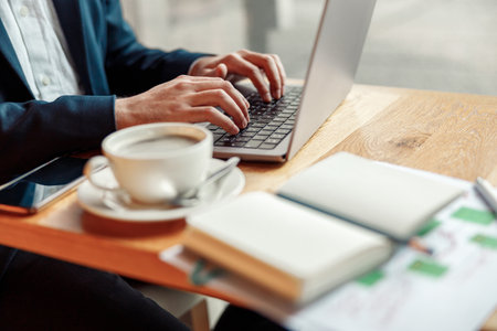 Close up of businessman hands working on laptop in coffee shop working spaceの写真素材