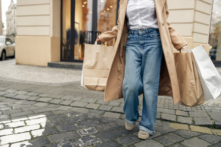 Close up of woman waving paper bags while walking on the city after successful shopping