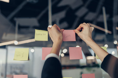 Businesswoman hands is sticking sticky notes on motivation board in officeの写真素材