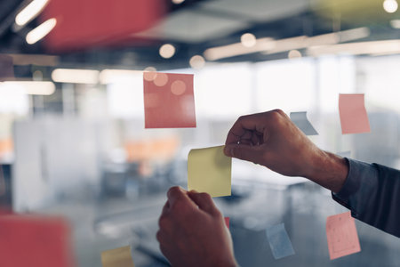 Businesswoman hands is sticking sticky notes on motivation board in officeの写真素材