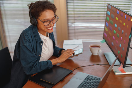 Woman graphic designer is using smartphone during work day in home office