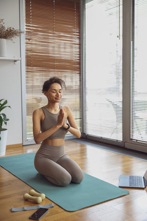Woman taking online yoga class from home. Female engaged in webcam meditation practice on computer
