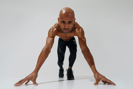 Bottom view of sportsman with naked torso is warming up on white studio background before workoutの写真素材