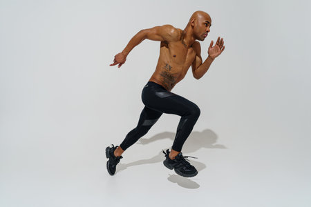 Active sporty man with naked torso jumping on white studio background. Sport and healthy lifestyleの写真素材