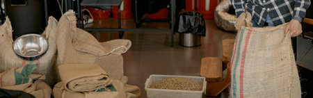 Worker hands holding bag with raw coffee beans standing on manufacturing