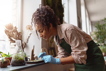 Professional woman florist takes care of seedlings in floral studio. Blurred backgroundの写真素材