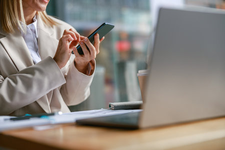 Close up of businesswoman use phone during working on laptop in cafe. Distance work conceptの写真素材