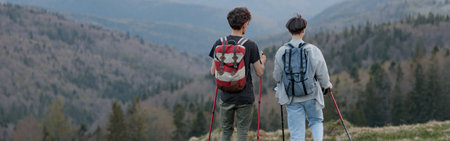 Back view on couple of travelers with walking sticks hiking high in mountains, Beauty of nature.