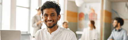 Smiling Businessman working laptop while sitting in modern office on colleagues backgroundの写真素材