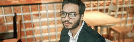 Handsome businessman in suit drinking coffee in cafe during break time sitting near windowの写真素材