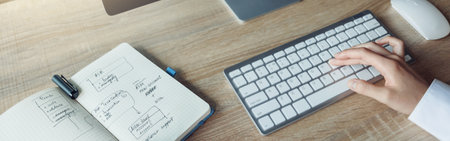 Close up of business woman hands working using keyboard of computer and making notes in office