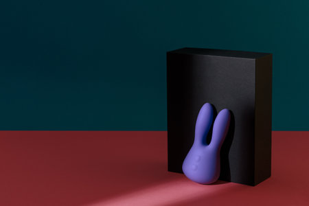 Violet dildo vibrator for clitoris with black gift box on colored background. Sex toy for adultの写真素材