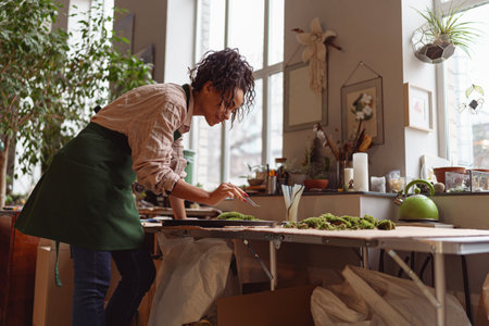 Woman decorator making green ikebana on tray with epoxy resin in florist workshopの写真素材