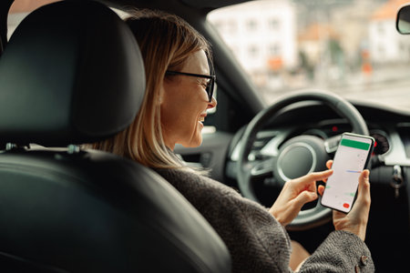 Female driver in glasses using phone with gps navigation app on screen while traveling by carの写真素材