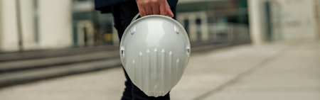 Close up of engineer in suit holding protective helmet and paper folder. Industrial conceptの写真素材