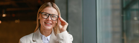 Businesswoman freelancer working on laptop while sitting in cafe near window and looking at cameraの写真素材