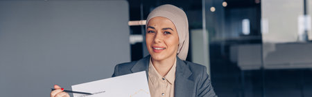 Smiling muslim businesswoman in hijab shows a graph of companys profit growth at meetingの写真素材