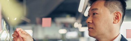 Close up of asian businessman is glues sticky notes on motivation board in modern officeの写真素材