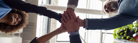 Happy group of multi ethnic coworkers stacked hands together as concept of corporate unity