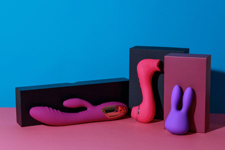 Different dildo vibrators and vacuum clitor stimulators with gift boxes on colored backgroundの写真素材