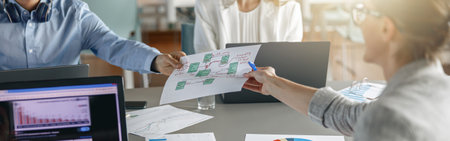 Group of busy coworkers working together analyzing the charts in modern officeの写真素材