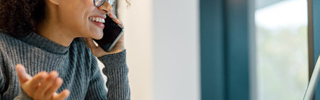 Close up of woman freelancer working laptop and talking phone while sitting in cozy coworking