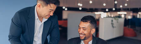 Two smiling coworkers working together on project in modern officeの写真素材