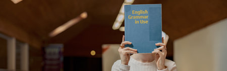 Young talented female student studying English Grammar while sit in university library