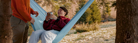 Young Caucasian man and woman laughing and having fun at hammock in wood. Happy together.の写真素材