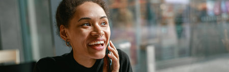 Smiling woman talking on phone with friends sitting in cafe near window. Lifestyle concept