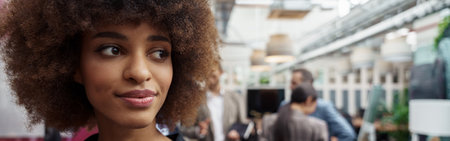 Smiling african businesswoman standing in modern office on colleagues backgroundの写真素材