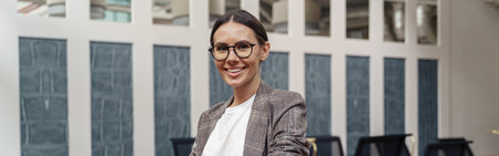 Portrait of smiling businesswoman in glasses standing in modern officeの写真素材