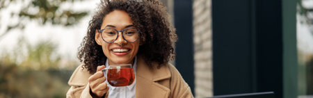 Woman freelancer working remotely and drinking tea while sitting on cafe terraceの写真素材