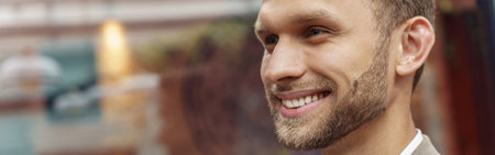 Smiling handsome businessman standing in office and looking at sideの写真素材