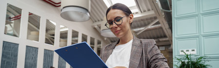 Portrait of smiling businesswoman with documents standing in modern office