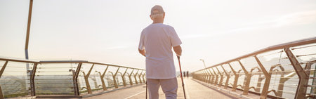 Mature sportsman practices Nordic walking on empty footbridgeの写真素材