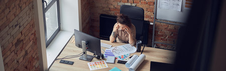 High angle view of tired woman touching her temples, having a stong headache while working on new...
