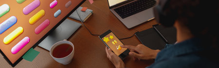 Woman graphic designer is using smartphone during work day in home office