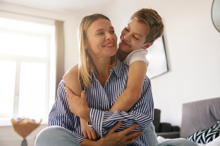 Cheerful son hugging happy mom with love and tenderness. Family, motherhood conceptの写真素材