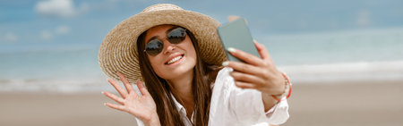 Young smiling woman in summer clothes make video call on phone at beach