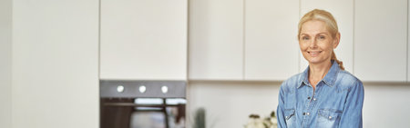 Smiling woman in rubber gloves ready for clean up in the kitchen. Detergents, sanitizer spray and gel in bottle on the surfaceの写真素材