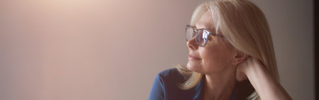 Calm mature woman in eyewear relaxing on a couch at home in the living room