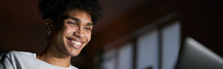 Happy alone. Joyful young guy smiling, watching comedy movie on a laptop and eating popcorn while...