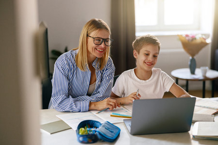 Female babysitter is teaching little boy use laptop application during studying