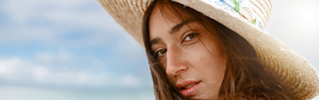 Portrait of beautiful woman in hat standing beach on the background of ocean during vacation