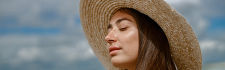 Portrait of beautiful woman in hat standing beach on the background of ocean during vacationの写真素材