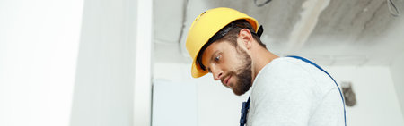 Male worker professional electrician in uniform installing electrical outlet in apartment after renovation workの写真素材