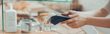 Female barista using terminal for contactless payment in cafeteriaの写真素材