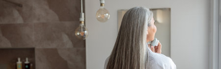 Female doing facial massage in modern bathroom in the morningの写真素材