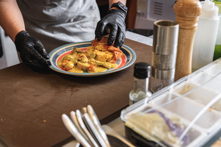 Close up of chef giving out finished dish at ordering station in open restaurant kitchenの写真素材